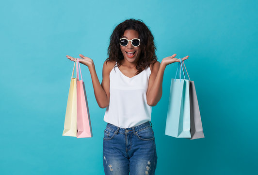 Happy beautiful young woman hand holding shopping bag isolated over blue background.