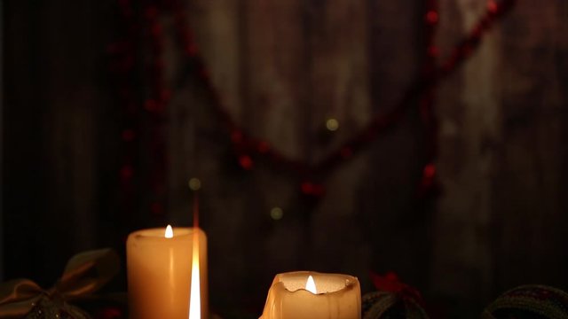 Warmth of Christmas: three lighted candles, one with a large flame in the foreground, red and golden balls, decoupage balls, satin gold ribbon, Christmas decoration filmed from top to bottom slide