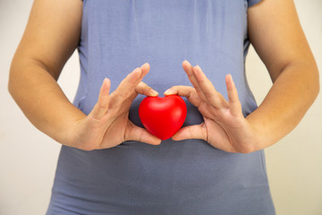 Pregnant women holding red hearts, Concept: Family expectations Happy lifestyle,mother in dress holds hands on belly,