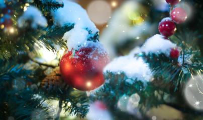 Festive christmas background. Multi-colored lights and balls on the branches of spruce. Blurry lights at night.