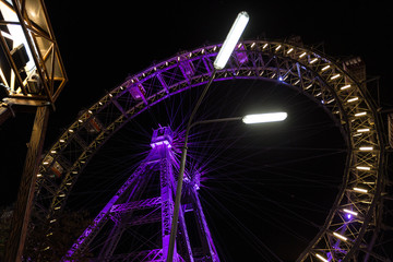 Looking up at a large purple ferris wheel at night