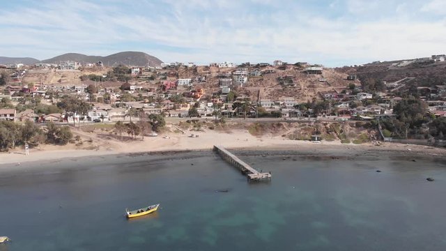 Aerial shot of beach, pier, going forward straight from the sea to the beach.
With boats on the sea, calm ocean.
Coquimbo, La Herradura, Chile.
4K 24fps