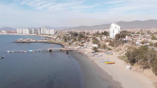 Aerial shot of a beach, and a pier, landing in tennis field, while people are playing, calm ocean.
Coquimbo, La Herradura, Chile.
4K 24fps