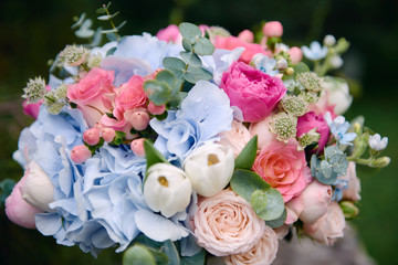 Close up of bridal bouquet of pink roses and blue hydrangea flowers on stone background outdoors, copy space. Wedding concept