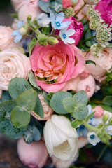 Close up of two golden wedding rings on bridal bouquet of pink and white roses outdoors, copy space. Selective focuse. Wedding concept