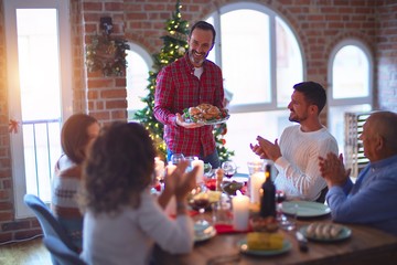 Beautiful family smiling happy and confident. Showing roasted turkey and applauding celebrating Christmas at home