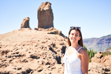 Young beautiful woman enjoying summer vacation on mountain landscape, smiling happy at Roque Nublo mountain top on Gran Canaria