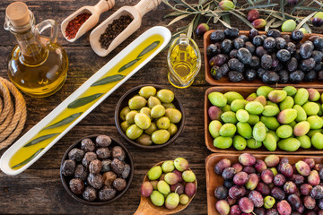 Many types of olive like green & black and olive oil at the rustic wooden table