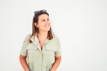 Beautiful girl leaning on white wall, young friendly woman smiling happy on a sunny day of summer