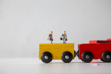 Naklejka na ściany i meble Miniature people car works on a multicolored Wooden car on a white wooden table, Creative background Teamwork for global transportation, Concept: Education for children learning in school