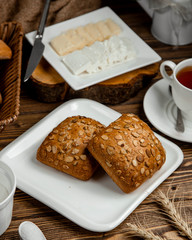 black bread covered with seeds, a plate of sliced cheese and a cup of tea