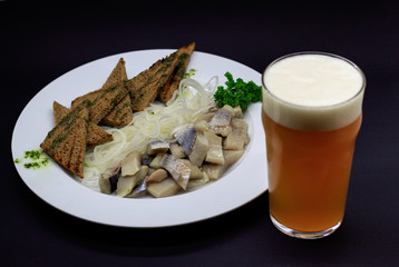 Croutons with herring on black background with beer