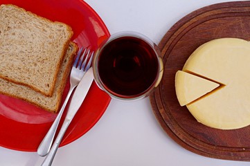 Top view of bread, red wine and sliced cheese.
