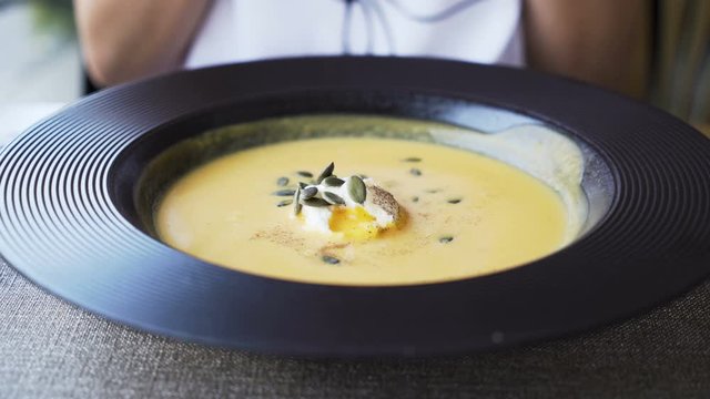 Woman eating pumpkin cream soup at restaurant