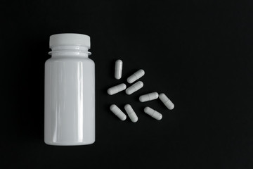 Capsules medication with a jar open in the background
