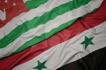 waving colorful flag of syria and national flag of abkhazia.