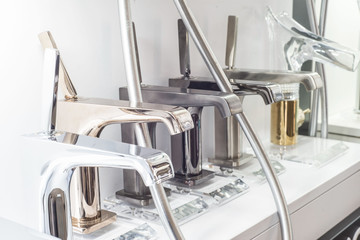 a variety of faucets taps on a white shelf in the store counter