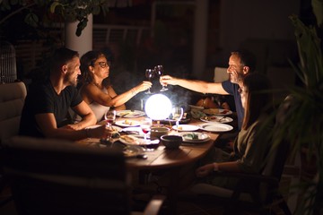 Beautiful family toasting with cup of wine on dinner smiling at terrace