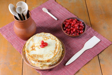 Stack of pancakes with dry cherry on the brown wooden table.  