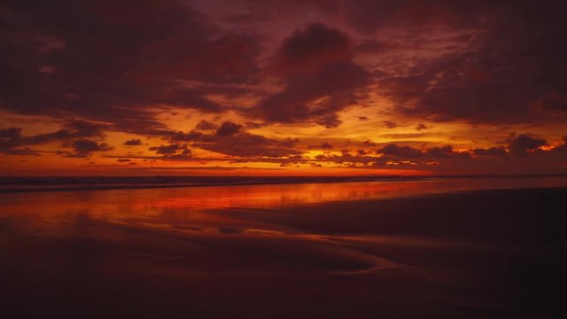 Beautiful sunset time-lapse cinemagraph / seamless video loop on a wide and remote sandy Pacific beach at Manuel Antonio National Park, Costa Rica. The clouds are colorizing the entire sky.
