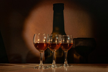 Three glasses with calvados stand on the table against the background of the bottle