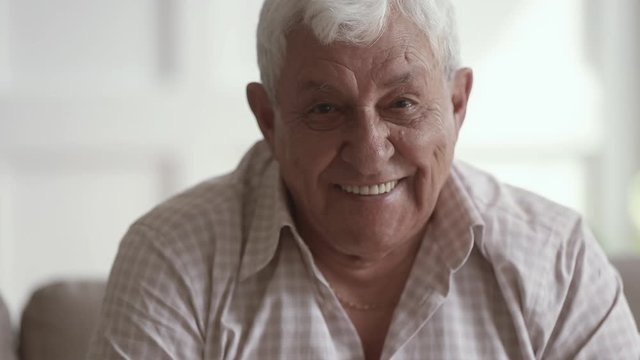 Happy mature grandfather looking at camera, sitting at home.