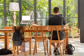 Man in casual cloths sitting at coffee shop working on laptop computer.