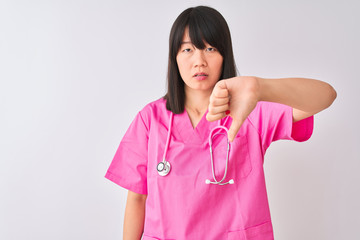 Young beautiful Chinese nurse woman wearing stethoscope over isolated white background looking unhappy and angry showing rejection and negative with thumbs down gesture. Bad expression.