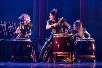 Traditional Japanese performance. Group of actresses drum taiko drums on the stage.