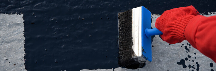 Worker applies bitumen mastic on the foundation