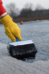 Worker applies bitumen mastic on the foundation