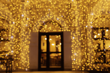 Fototapeta premium Bright bokeh texture, defocused door and blurred christmas decoration outdoors. New year background.