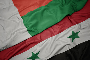 Obraz premium waving colorful flag of syria and national flag of madagascar.