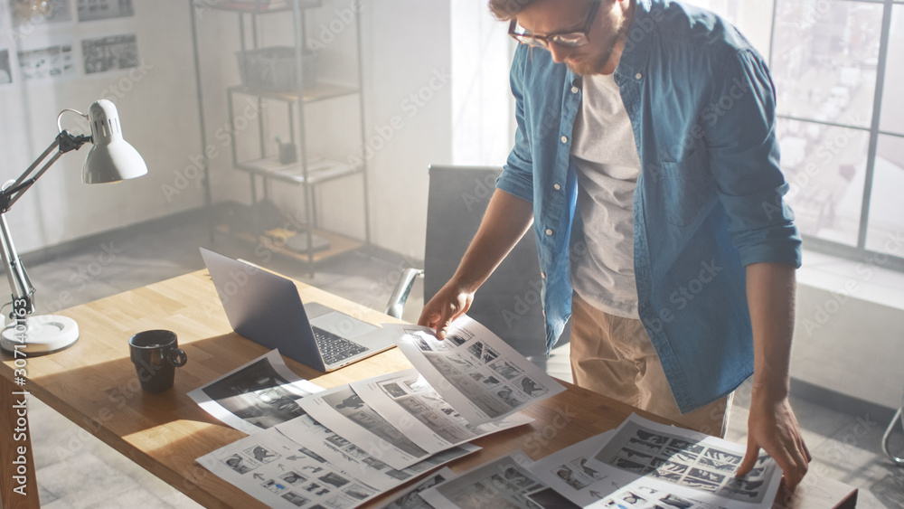 Poster creative designer works on a storyboard, looks at his sketches and concepts, choosing the best drawi