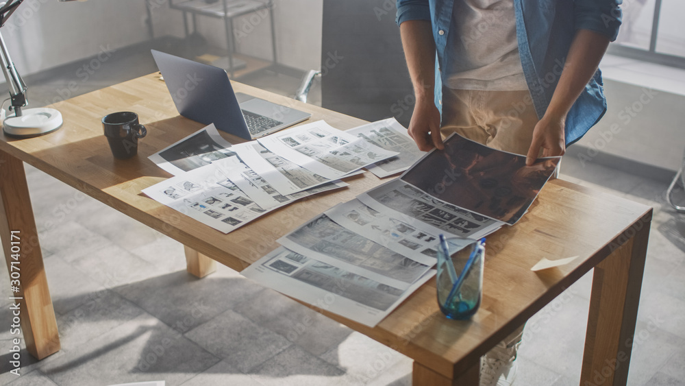 Poster creative designer works on a storyboard, looks at his sketches and concepts, choosing the best drawi