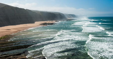 PORTUGAL, Praia do Magoito - Magoito Beach viewed from above. Magoito view with big vawes and misty, foggy air in September. Atlantic ocean coast at Portugal near Sintra and Lisbon.