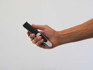 Close-up, shaving trimer in hand. White background.