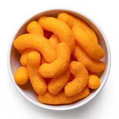 Extruded cheese puffs in a white ceramic bowl isolated on white. Top view.