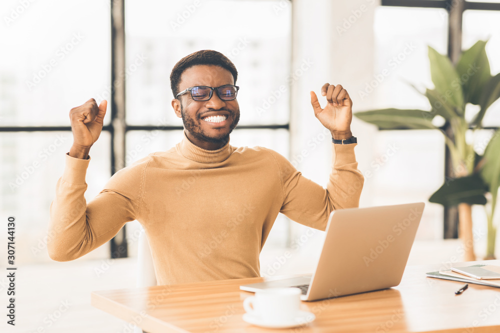 Wall mural Ecstatic black guy celebrating his success at work