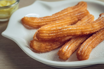 Churros with sugar on plate and cheese dip