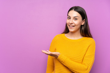 Young woman over isolated purple background extending hands to the side for inviting to come