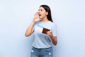 Naklejka premium Traveler woman with boarding pass over isolated blue wall shouting with mouth wide open