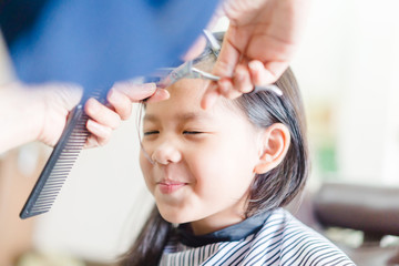 Asian little girl haircut. hairdresser, beauty salon.Cute little asian girl in hairdressing salon.