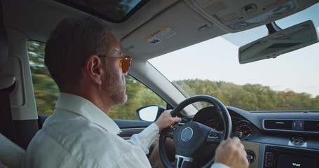 Casual businessman using hitech device abilities driving car in summer twilight. Shot for animation. Finger tapping, swapping cyber touchscreen. Business people. Successful guy. Comfortable journey.