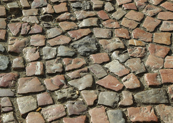 An old stoneblock pavement cobbled with natural stone blocks with gaps between blocks