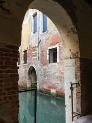 View from an arch on a stone house on the edge of a Venice canal