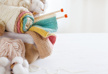 Knitting wool and knitting needles in pastel colors on white background. Cotton bolls. Copy space