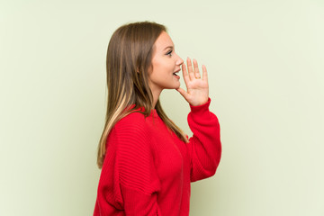 Teenager girl over isolated green background shouting with mouth wide open