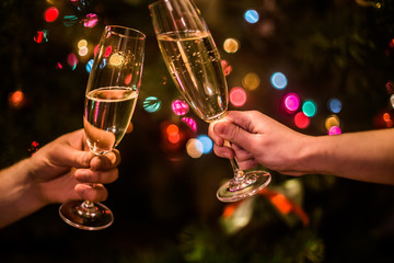 Glass with champagne in hand on a Christmas tree background