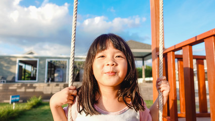 5 years old.Asian child girl playing on playground in outdoor park.Happy Little asian girl playing swing with her friends.Happy moment and good emotion.